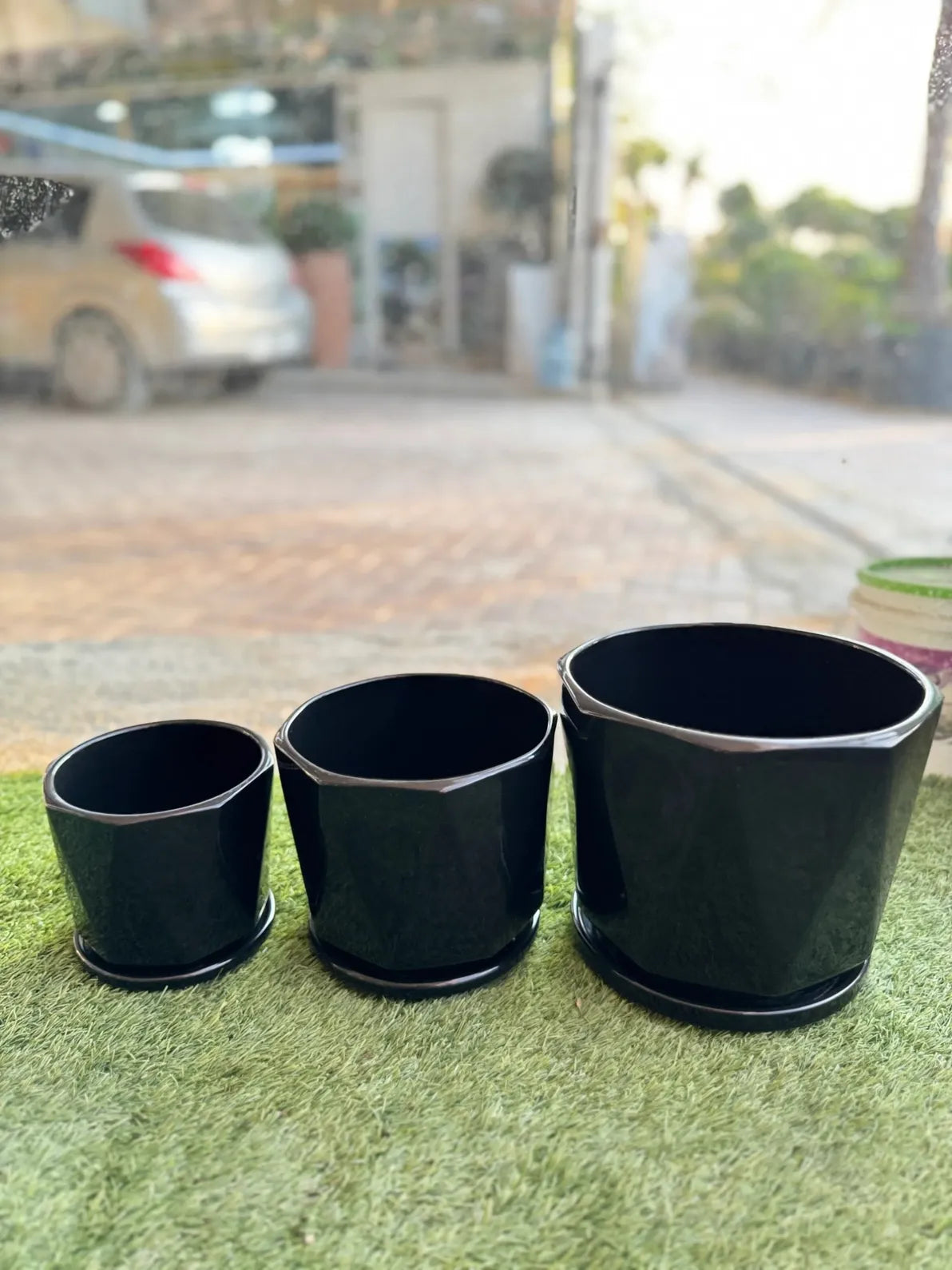 Sleek black geometric ceramic pots with drainage trays, modern stylish planter set in the UAE.