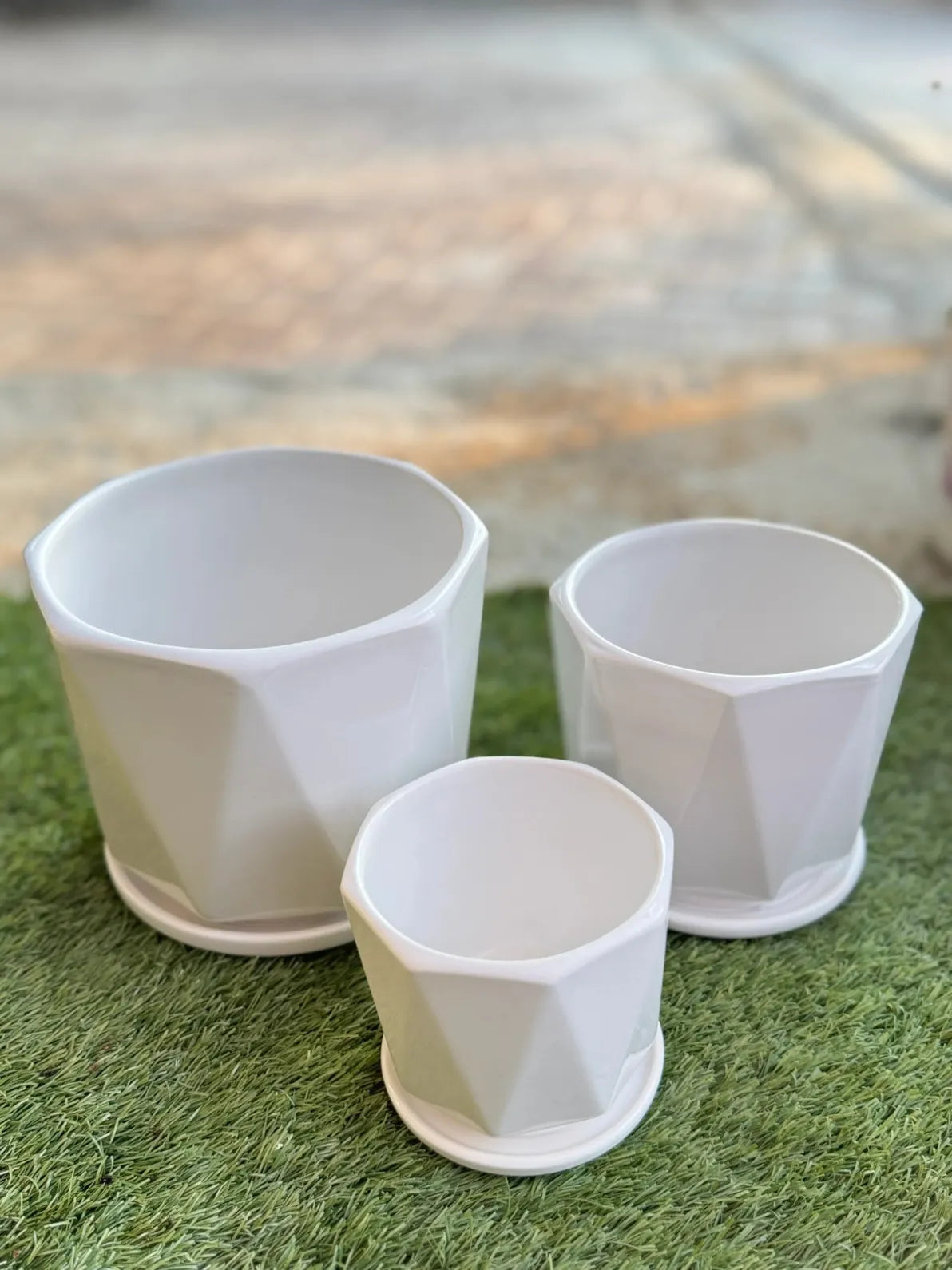 Clean white geometric ceramic pots with drainage trays, modern minimalist planter set in the UAE.